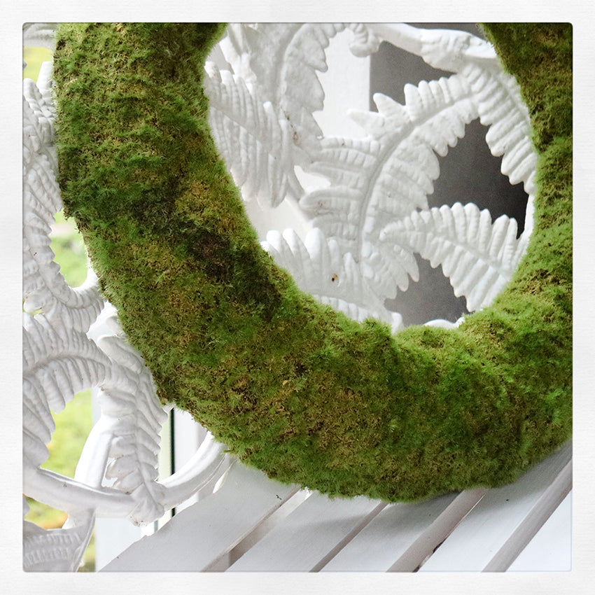 Detalj av en konstgjord krans, i Mossa på en bänk