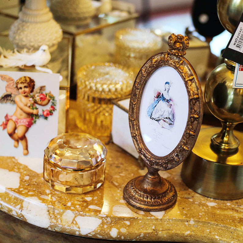 Förgylld rund fotoram med fot och krona  i rumsmiljö