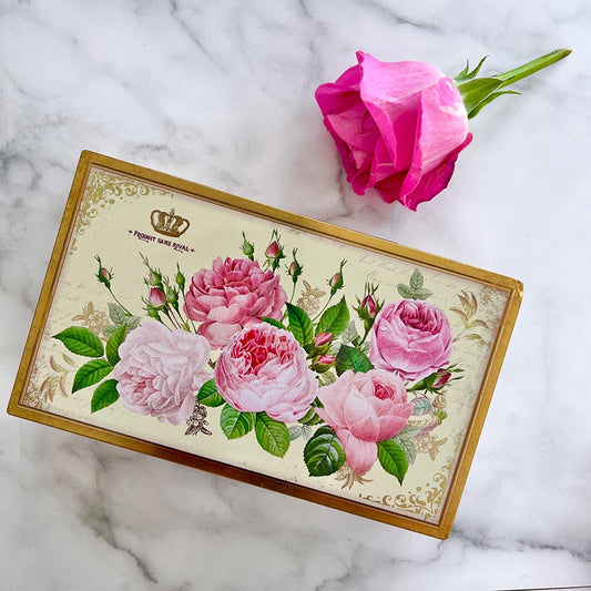 Rektangulär plåtask dekorerad med rosor. bredvid asken ligger en rosa ros.