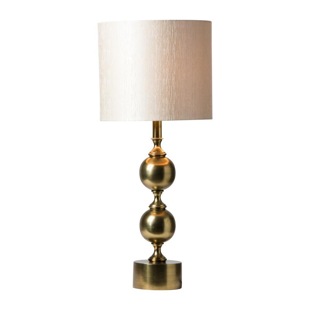 En mässingslampfot med en lampskärm med en krämigt benvit utsida och guldig insida.